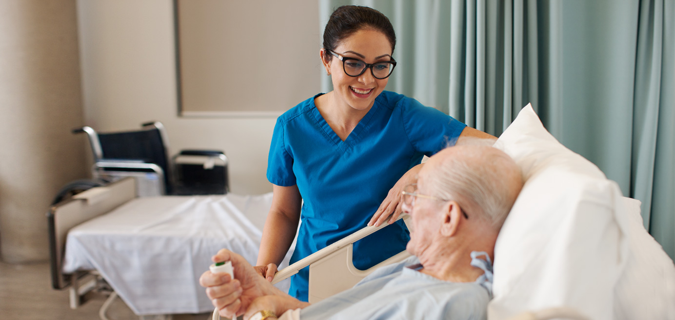 Nurse standing beside patient laying in hospital bed