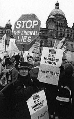 BCNU member holding sign standing in front of the legislature building