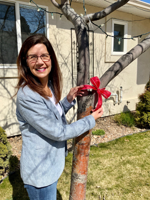 Christine Sorensen ties a ribbon on a tree