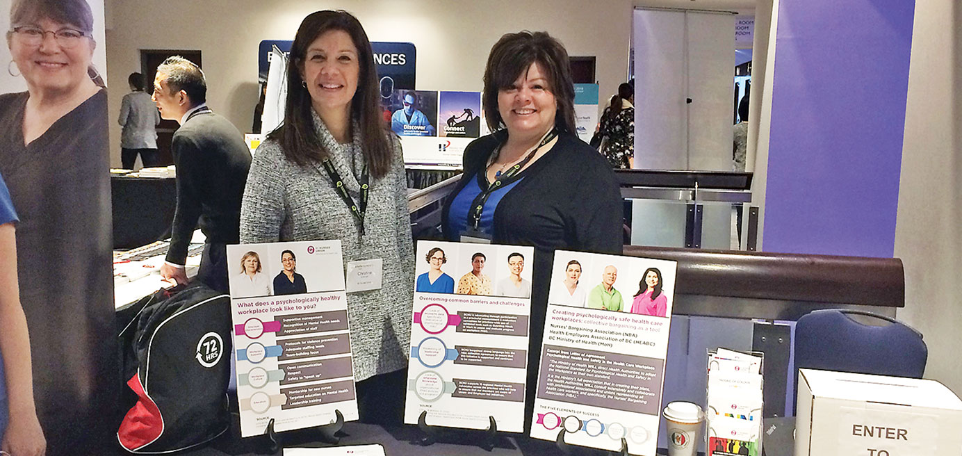 BCNU Acting President Christine Sorensen (left) and Acting Vice President Adriane Gear (right) standing behind table with BCNU materials to promote psychological health at BC Patient Safety and Quality Council’s annual forum 
