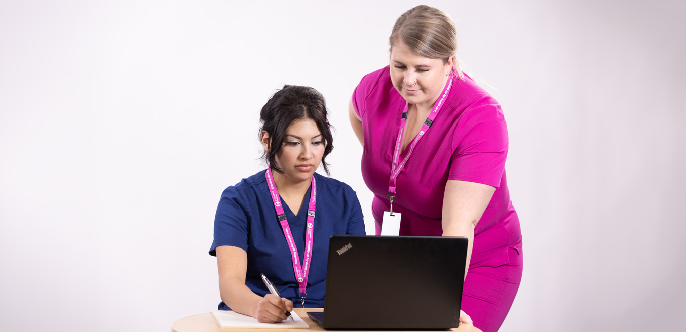 A bunch of nurses gathered around a laptop